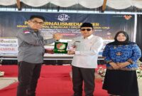 Ketua Umum Pro Jurnalismedia Siber  (PJS) Mahmud Marhaba menyerahkan cinderamata kepda Bupati Tojo Una- una Ilham Lawidu yang didampingi wakil bupati Hj Surya. (ist)
